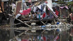 A woman hangs newly laundered clothes at a damaged house after Typhoon Rammasun battered the town for two days, in Rosario, Cavite city, south of Manila July 18, 2014. REUTERS